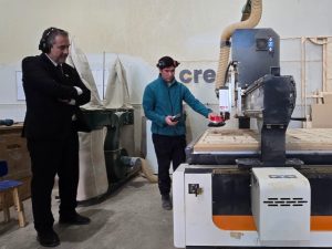 Un hombre manipula una máquina de corte de madura, junto al gerente general de Sercotec.