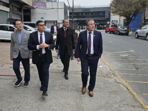 El gerente general de Sercotec, junto al director regional de Sercotec, el presidente de la Cámara de Comercio de Patronato y el presidente de la Asociación Coreana en Chile caminan juntos por una acera pública en la zona comercial de Patronato. Al fondo se aprecian locales comerciales, automóviles estacionados y otras personas transitando por la calle en un día nublado.