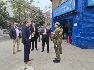 El gerente general de Sercotec, junto al director regional de Sercotec y el presidente de la Cámara de Comercio de Patronato conversan en la calle con dos funcionarias de Carabineros de Chile que visten su uniforme institucional verde con chalecos antibalas. Al fondo se encuentra un minimarket con fachada azul.
