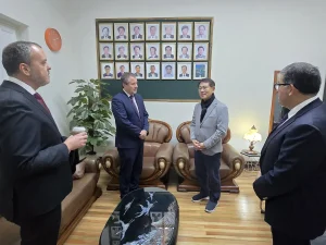 El gerente general de Sercotec, junto al director regional de Sercotec, el presidente de la Cámara de Comercio de Patronato y el presidente de la Asociación Coreana en Chile se encuentran de pie en una oficina con piso de madera. Al fondo destaca un gran cuadro verde en la pared que contiene filas de retratos fotográficos enmarcados.