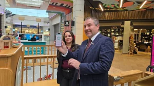 El gerente general de Sercotec sonríe mientras muestra la pantalla de un teléfono celular con una aplicación digital, junto a la dueña de la empresa Jovi Park.