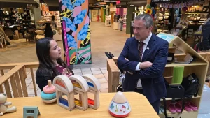 El gerente general de Sercotec escucha atentamente a la dueña de la empresa Jovi Park junto a un mostrador con juguetes didácticos.