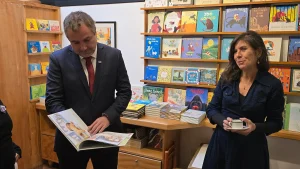 El gerente general de Sercotec y una de las representantes de la cooperativa Clic hojean juntos un libro infantil ilustrado.