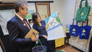 Una representante de la cooperativa Clic le muestra y explica un calendario ilustrado grande al gerente general de Sercotec.