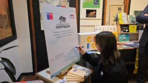 La secretaria ejecutiva de Economía Creativa firma un gran cartel que dice "Firma de compromiso por la creación y fortalecimiento de cooperativas culturales".