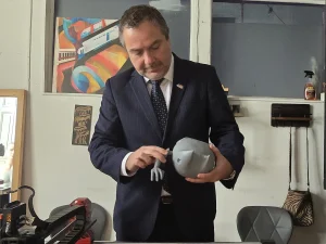 El gerente general de Sercotec sostiene y observa de cerca un juguete gris impreso en 3D en el taller de Cachivarte.