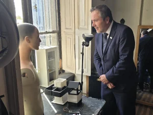 El gerente general de Sercotec inclina la cabeza para observar de cerca un maniquí de torso sin cabeza y unos prototipos de cajas blancas en una mesa.