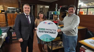 El gerente general de Sercotec, la jefa de la oficina de Sostenibilidad FEN UChile y el fundador de Reciklast posan sosteniendo un cartel del "Sello Impacta Sustentable" y un premio de madera en el taller de la empresa.
