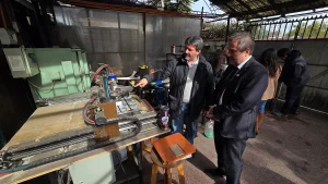 El fundador de Reciklast le señala y explica detalles de una gran máquina CNC (control numérico computarizado) al gerente general de Sercotec en un área de trabajo exterior.