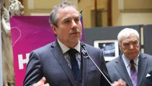 Plano medio del gerente general de Sercotec, vestido de traje oscuro, declarando ante un micrófono, con el gerente general de Sofofa al fondo de la imagen.