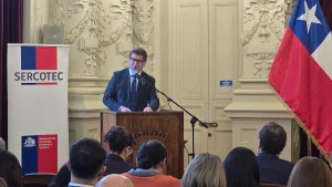 El ministro de Economía pronuncia un discurso desde un podio de madera en un salón institucional, frente a una audiencia en primer plano y un banner de Sercotec.