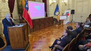 Vista general de la sala donde el gerente general de Sofofa expone desde el podio ante la audiencia sentada, con una pantalla al fondo que muestra la gráfica "Hazlo con IA".