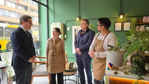 El ministro de Economía y el gerente general de Sercotec conversan animadamente con los dos dueños de Inti Mapu cerca de la entrada de la pastelería. La dueña sonríe mientras el dueño escucha.