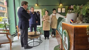 El ministro de Economía y el gerente general de Sercotec observan la vitrina de pasteles del local Inti Mapu guiados por la dueña, mientras el otro dueño está parado cerca del mostrador principal.